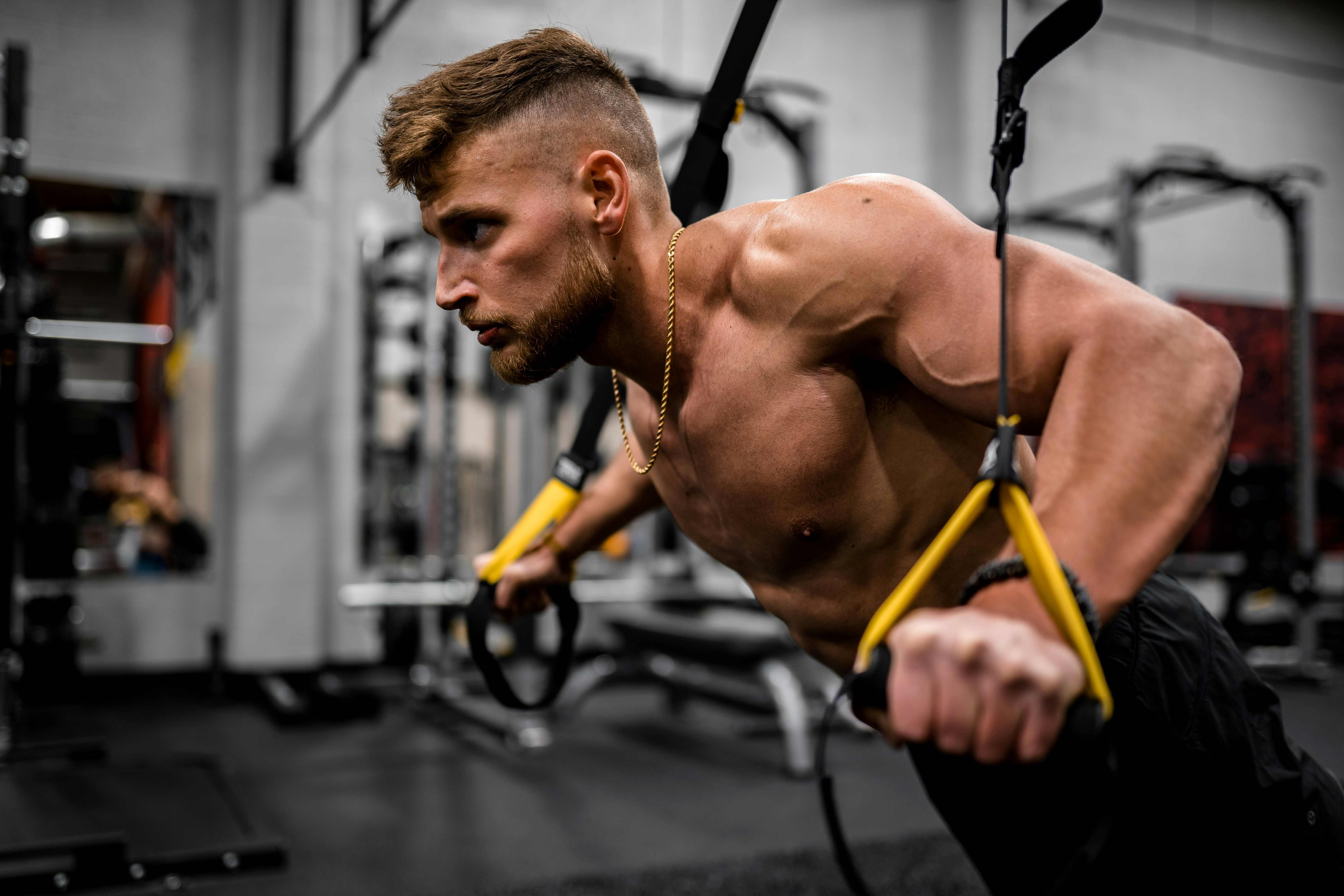 Muž cvičí kliky na TRX závěsném posilovacím systému